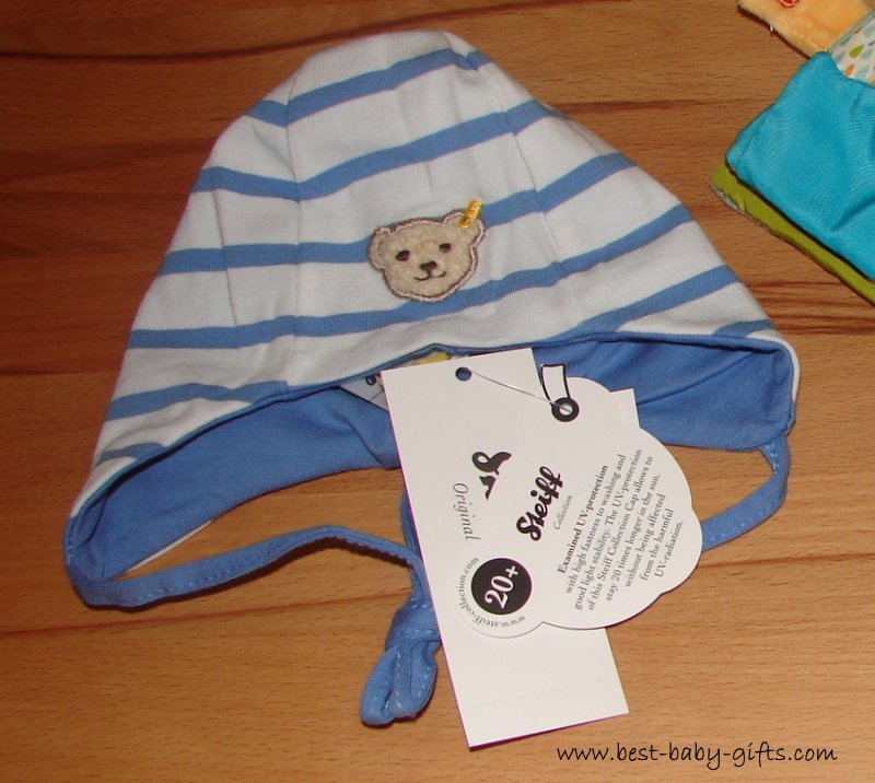 a blue and white baby hat with the iconic Steiff teddy bear logo
