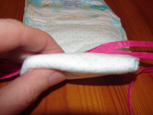fingers rolling a diaper with ribbon inside