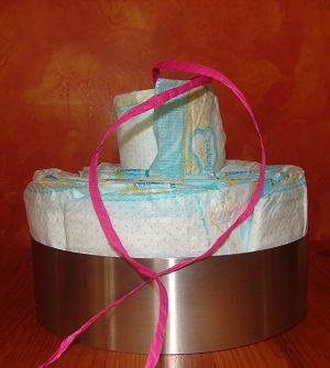 cake setting ring with diapers and last diaper with ribbon inside placed on top but still attached