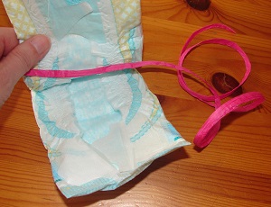 fingers holding diaper and pink ribbon inside