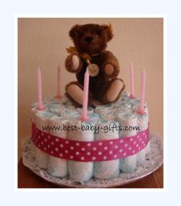 one tier girl diaper cake with a cuddly teddy bear and some pink candles on top