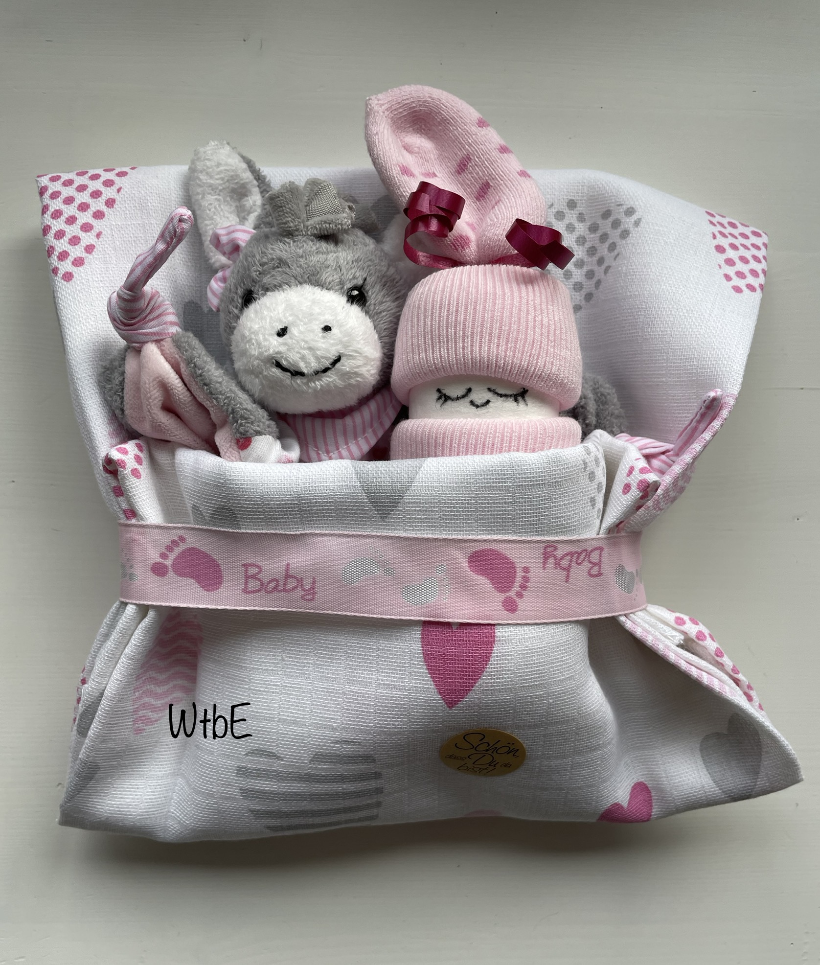 small diaper cake: diaper baby and a cuddly donkey toy in a cloth
